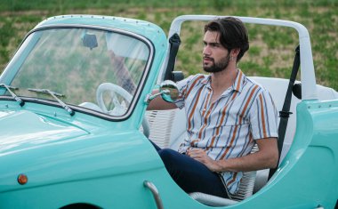 İtalyan esmer çocuk, klasik bir arabanın yanında poz veriyor. Autobianchi Bianchina Spiaggina. Yüksek kalite fotoğraf