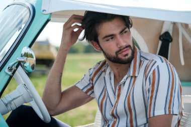 İtalyan esmer çocuk, klasik bir arabanın yanında poz veriyor. Autobianchi Bianchina Spiaggina. Yüksek kalite fotoğraf