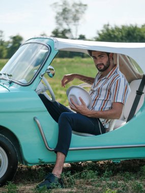 İtalyan esmer çocuk, klasik bir arabanın yanında poz veriyor. Autobianchi Bianchina Spiaggina. Yüksek kalite fotoğraf