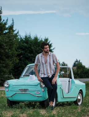 İtalyan esmer çocuk, klasik bir arabanın yanında poz veriyor. Autobianchi Bianchina Spiaggina. Yüksek kalite fotoğraf