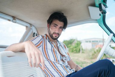 İtalyan esmer çocuk, klasik bir arabanın yanında poz veriyor. Autobianchi Bianchina Spiaggina. Yüksek kalite fotoğraf