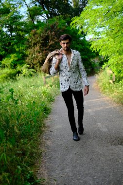 Yakışıklı, koyu renk saçlı, şık tişörtsüz bir İtalyan. Gün batımında elinde bavulla yürüyor. Yüksek kalite fotoğraf