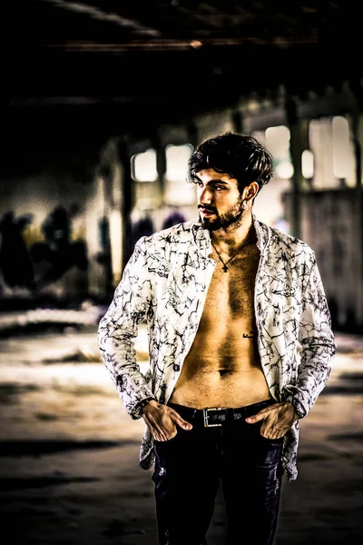 Terk edilmiş fabrikada gömleksiz, siyah saçlı yakışıklı bir İtalyan. Yüksek kalite fotoğraf