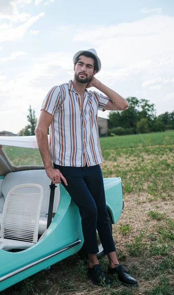 İtalyan esmer çocuk, klasik bir arabanın yanında poz veriyor. Autobianchi Bianchina Spiaggina. Yüksek kalite fotoğraf