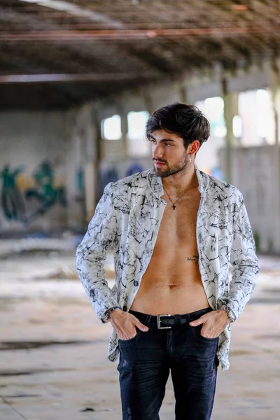 Terk edilmiş fabrikada gömleksiz, siyah saçlı yakışıklı bir İtalyan. Yüksek kalite fotoğraf