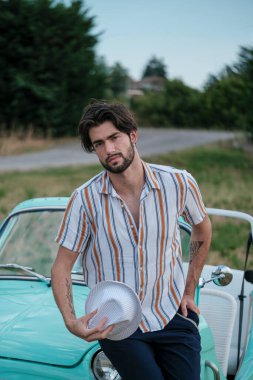 İtalyan esmer çocuk, klasik bir arabanın yanında poz veriyor. Autobianchi Bianchina Spiaggina. Yüksek kalite fotoğraf