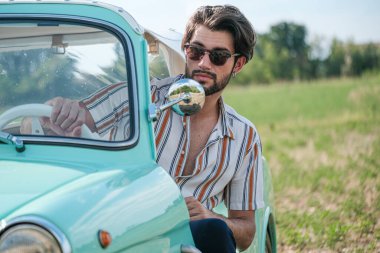 İtalyan esmer çocuk, klasik bir arabanın yanında poz veriyor. Autobianchi Bianchina Spiaggina. Yüksek kalite fotoğraf