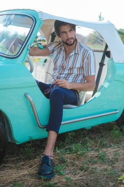 İtalyan esmer çocuk, klasik bir arabanın yanında poz veriyor. Autobianchi Bianchina Spiaggina. Yüksek kalite fotoğraf