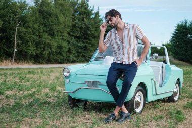 İtalyan esmer çocuk, klasik bir arabanın yanında poz veriyor. Autobianchi Bianchina Spiaggina. Yüksek kalite fotoğraf