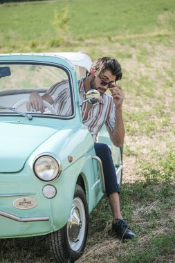 İtalyan esmer çocuk, klasik bir arabanın yanında poz veriyor. Autobianchi Bianchina Spiaggina. Yüksek kalite fotoğraf
