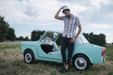 İtalyan esmer çocuk, klasik bir arabanın yanında poz veriyor. Autobianchi Bianchina Spiaggina. Yüksek kalite fotoğraf
