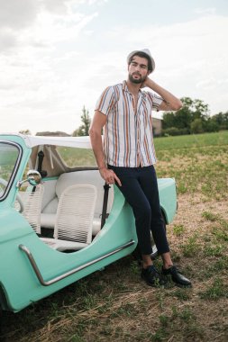 İtalyan esmer çocuk, klasik bir arabanın yanında poz veriyor. Autobianchi Bianchina Spiaggina. Yüksek kalite fotoğraf