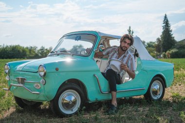 İtalyan esmer çocuk, klasik bir arabanın yanında poz veriyor. Autobianchi Bianchina Spiaggina. Yüksek kalite fotoğraf