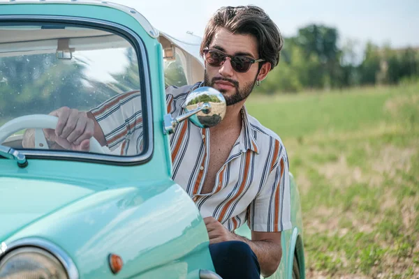 İtalyan esmer çocuk, klasik bir arabanın yanında poz veriyor. Autobianchi Bianchina Spiaggina. Yüksek kalite fotoğraf