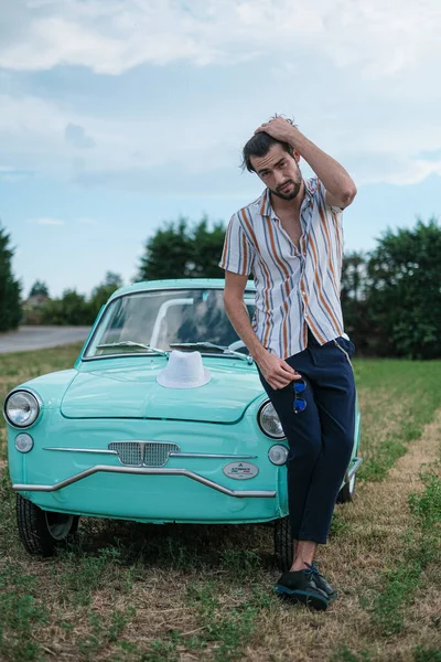 İtalyan esmer çocuk, klasik bir arabanın yanında poz veriyor. Autobianchi Bianchina Spiaggina. Yüksek kalite fotoğraf