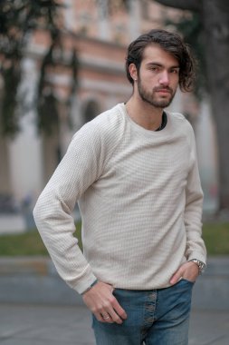 Şehir merkezinde sakallı, beyaz kazaklı yakışıklı, siyah saçlı bir İtalyan. Yüksek kalite fotoğraf