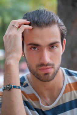 Çizgili tişörtlü, yakışıklı, siyah saçlı çocuğun portresi. Yüksek kalite fotoğraf