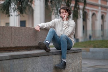 Şehir merkezinde sakallı, beyaz kazaklı yakışıklı, siyah saçlı bir İtalyan. Yüksek kalite fotoğraf