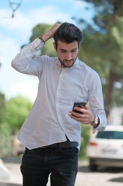 Güzel adam merkezden geçip akıllı telefona bakıyor. Yüksek kalite fotoğraf