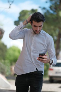 Güzel adam merkezden geçip akıllı telefona bakıyor. Yüksek kalite fotoğraf