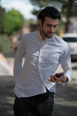 Güzel adam merkezden geçip akıllı telefona bakıyor. Yüksek kalite fotoğraf