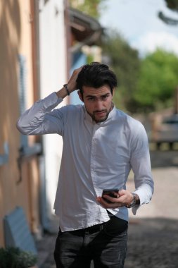 Güzel adam merkezden geçip akıllı telefona bakıyor. Yüksek kalite fotoğraf