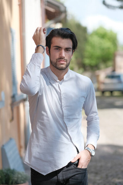 Красивый парень ходит по центру в белой рубашке. Высокое качество фото