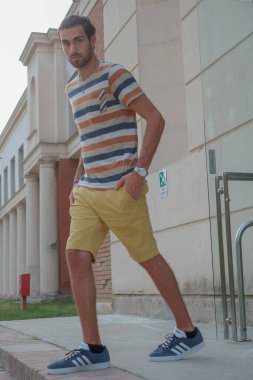 Güzel çocuk bermuda şortu ve çizgili gömleğiyle geziniyor. Yüksek kalite fotoğraf