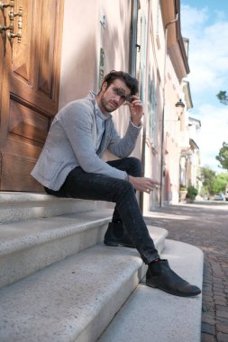 Ceketli, siyah saçlı yakışıklı İtalyan bir adam merdivende oturuyor. Yüksek kalite fotoğraf