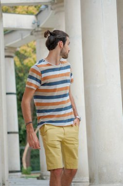 Güzel çocuk bermuda şortu ve çizgili gömleğiyle geziniyor. Yüksek kalite fotoğraf