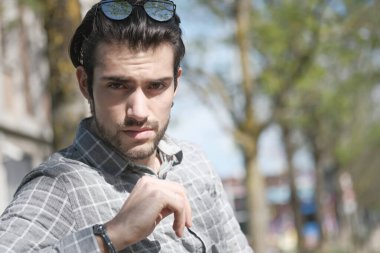 Yakışıklı, siyah saçlı, güneş gözlüklü, bankta oturan adam. Yüksek kalite fotoğraf