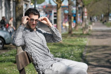 Yakışıklı, siyah saçlı, güneş gözlüklü, bankta oturan adam. Yüksek kalite fotoğraf