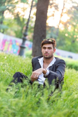 Yakışıklı, siyah saçlı, yeşil tarlada oturan adam. Yüksek kalite fotoğraf