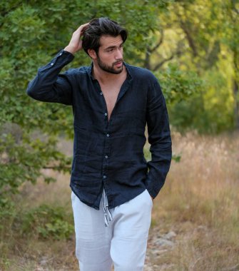 Kuru çimenlerde gömleği olan yakışıklı, siyah saçlı bir İtalyan. Yüksek kalite fotoğraf