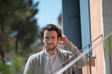 Yakışıklı, siyah saçlı, güneşli bir günde korkuluklara yaslanan bir İtalyan. Yüksek kalite fotoğraf