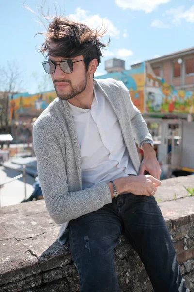 Handsome Italian Dark Haired Guy Jacket Sitting Low Wall Sunny — стоковое фото