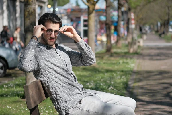 Yakışıklı, siyah saçlı, güneş gözlüklü, bankta oturan adam. Yüksek kalite fotoğraf