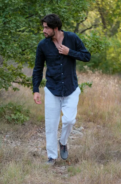 Kuru çimenlerde gömleği olan yakışıklı, siyah saçlı bir İtalyan. Yüksek kalite fotoğraf