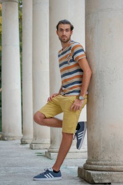 Güzel çocuk bermuda şortu ve çizgili gömleğiyle geziniyor. Yüksek kalite fotoğraf