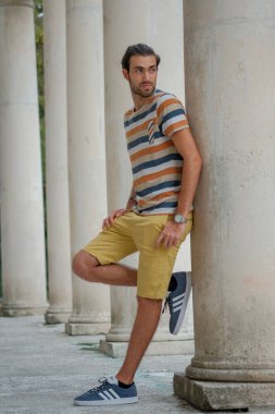 Güzel çocuk bermuda şortu ve çizgili gömleğiyle geziniyor. Yüksek kalite fotoğraf