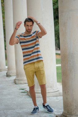 Güzel çocuk bermuda şortu ve çizgili gömleğiyle geziniyor. Yüksek kalite fotoğraf