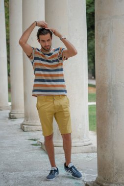 Güzel çocuk bermuda şortu ve çizgili gömleğiyle geziniyor. Yüksek kalite fotoğraf