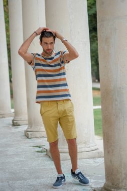 Güzel çocuk bermuda şortu ve çizgili gömleğiyle geziniyor. Yüksek kalite fotoğraf