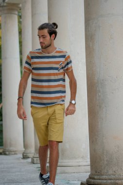 Güzel çocuk bermuda şortu ve çizgili gömleğiyle geziniyor. Yüksek kalite fotoğraf