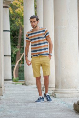 Güzel çocuk bermuda şortu ve çizgili gömleğiyle geziniyor. Yüksek kalite fotoğraf