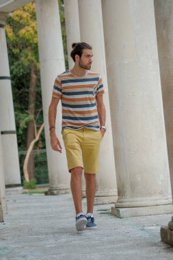 Güzel çocuk bermuda şortu ve çizgili gömleğiyle geziniyor. Yüksek kalite fotoğraf