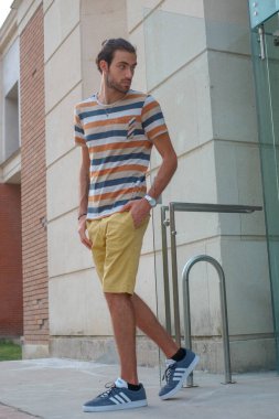 Güzel çocuk bermuda şortu ve çizgili gömleğiyle geziniyor. Yüksek kalite fotoğraf