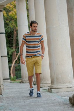 Güzel çocuk bermuda şortu ve çizgili gömleğiyle geziniyor. Yüksek kalite fotoğraf