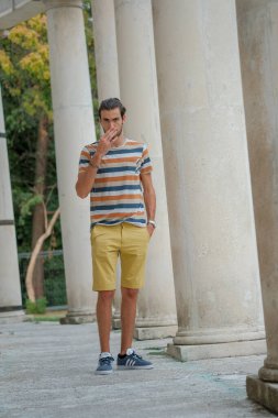 Güzel çocuk bermuda şortu ve çizgili gömleğiyle geziniyor. Yüksek kalite fotoğraf