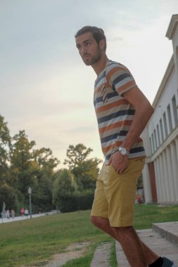 Güzel çocuk bermuda şortu ve çizgili gömleğiyle geziniyor. Yüksek kalite fotoğraf